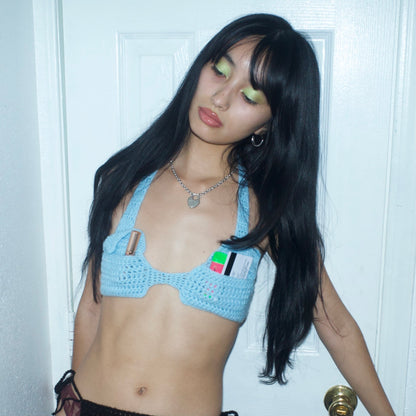 Model wearing the Bailey Prado Envelope Bra, a hand-crocheted baby blue halter top with adjustable neck and back ties.