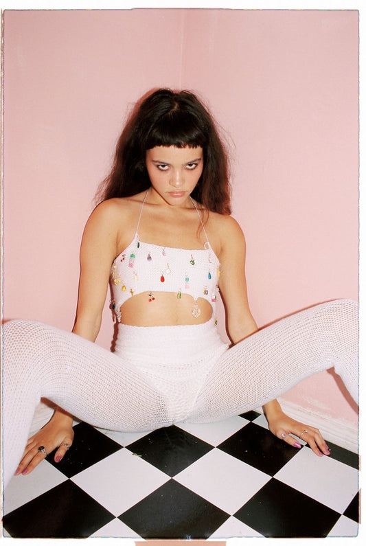 Model wearing the Bailey Prado Original Charm Top, a handmade knit halter top with colorful charm embellishments and adjustable lace-up back.