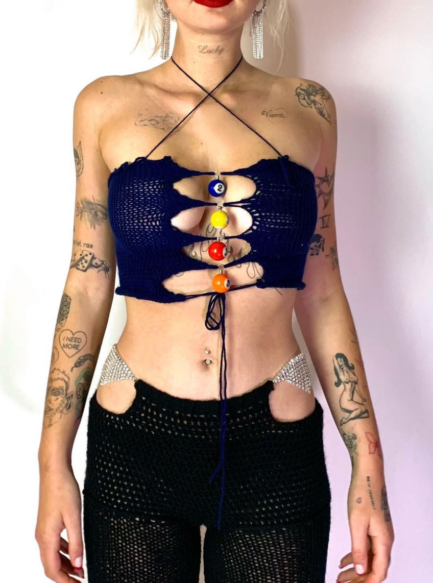 Model wearing the Bailey Prado Pool Ball Top, a navy blue crochet halter top with colorful pool ball charms and an adjustable lace-up front.