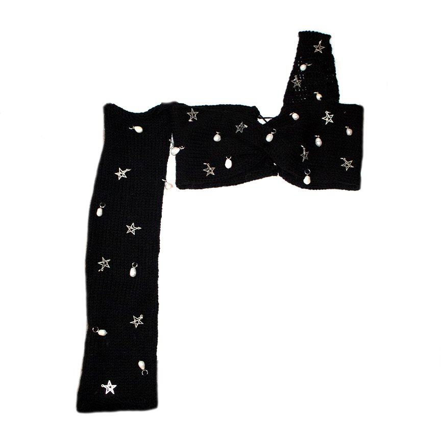 Bailey Prado Starlight Charm Top featuring a black crochet twist crop top with freshwater pearls, silver star charms, one off-the-shoulder long sleeve, and an adjustable lace-up back.
