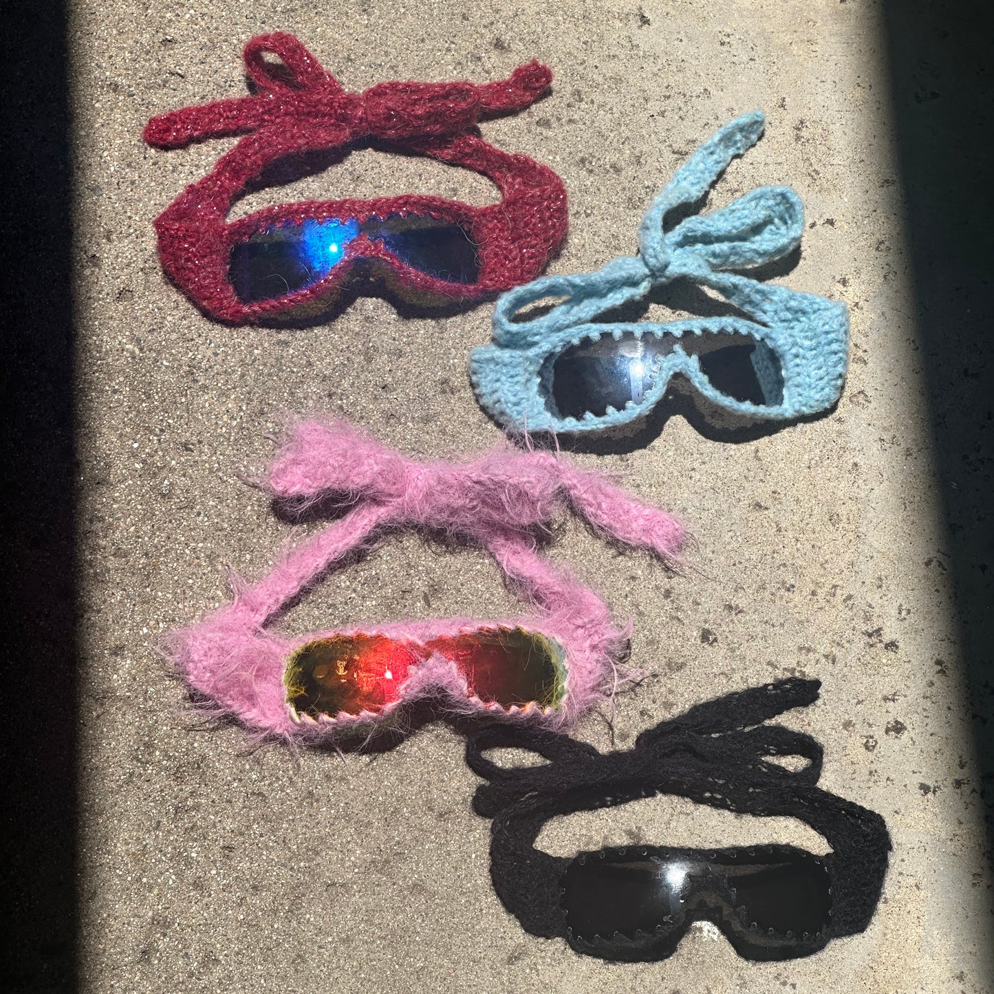 Handmade knitted sunnies by Bailey Prado featuring UV400 protective lenses, available in red, black, pink, and blue.